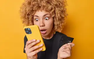 Ragazza riccia che guarda stupita lo smartphone